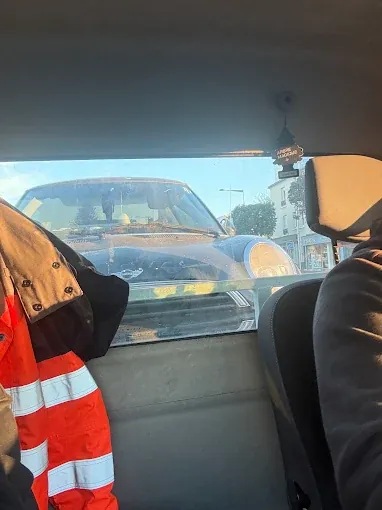 Dépanneur en gilet haute visibilité dans la cabine de la dépanneuse, véhicule remorqué visible derrière